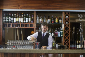 A bartender behind the bar pouring cocktails